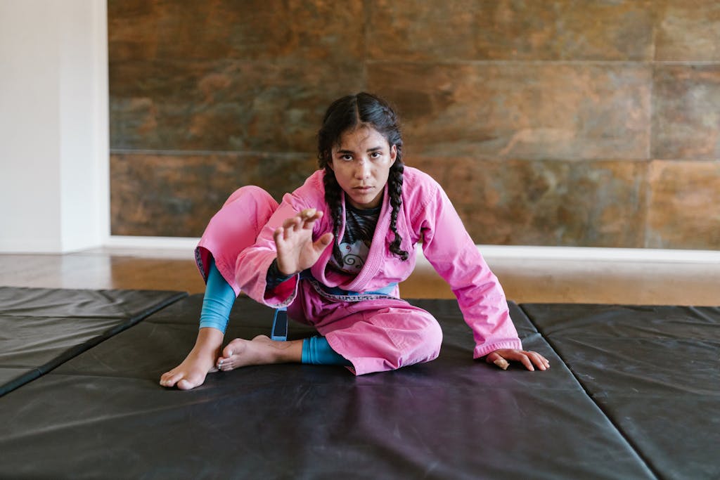 A Woman with Braided Hair Wearing a Pink Gi. Women's Brazilian Jiu Jitsu is offered at Combat Social Club in San Antonio, TX.