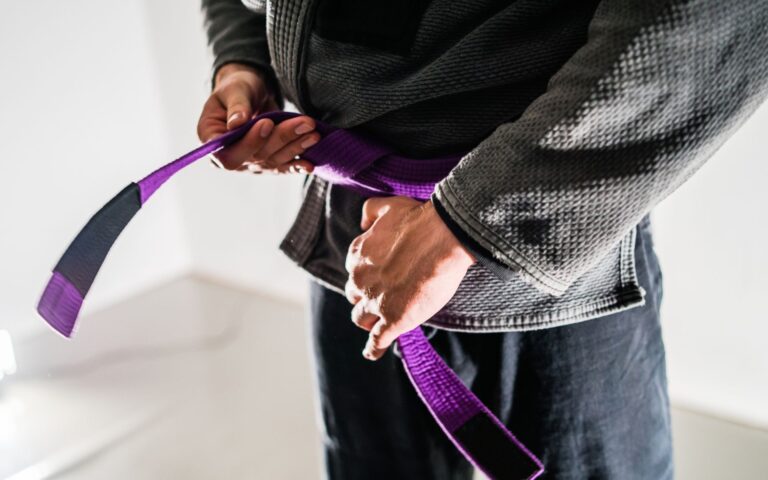 A purple belt ties his belt before a BJJ class in San Antonio. Judo vs. BJJ